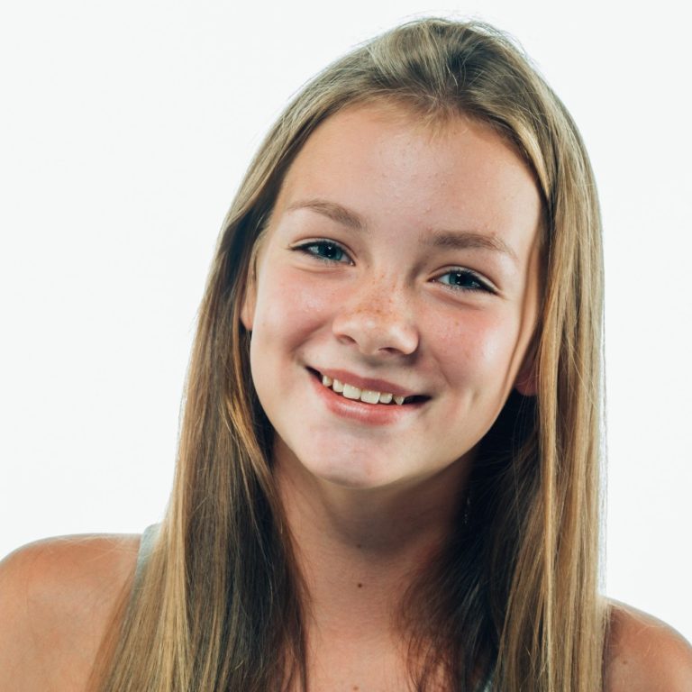 Lächelndes Mädchen mit langen, glatten Haaren und freundlichem Gesichtsausdruck.