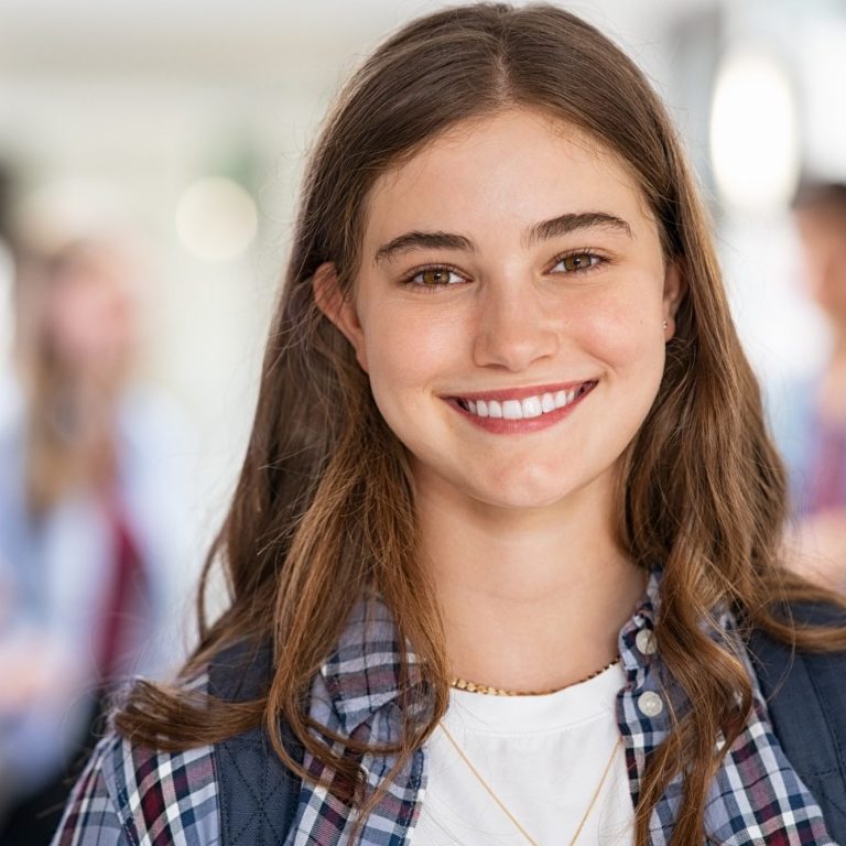 Junge Frau mit lässigem Outfit und freundlichem Lächeln in einer Schule.